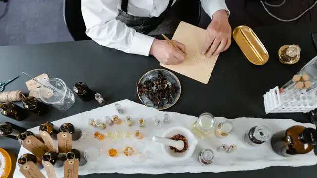 Almofariz e ingredientes aromáticos em bancada de trabalho, representando a classificação e composição dos perfumes