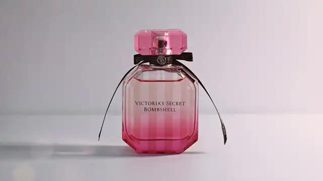 Frasco de perfume importado feminino em tom rosa sobre superfície clara e elegante