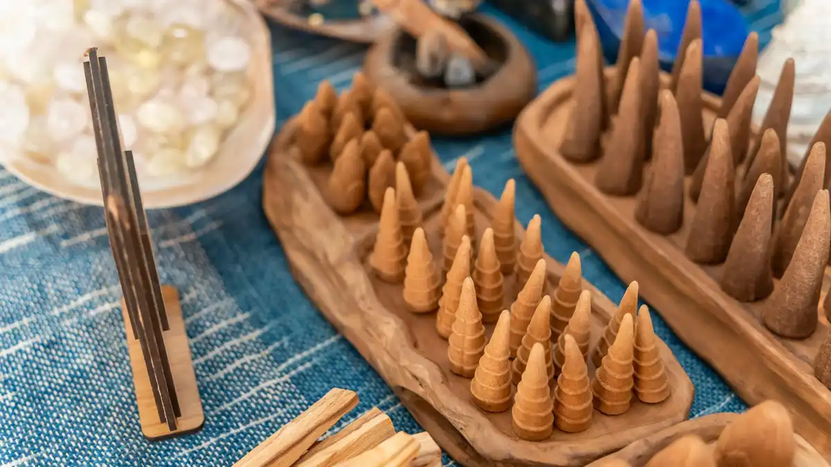 Cones de incenso e madeiras aromáticas em bandejas de madeira sobre tecido azul — evoca matérias-primas amadeiradas como o sândalo