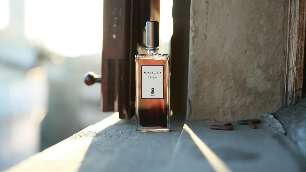 Frasco de perfume âmbar sobre parapeito de pedra com luz dourada de manhã