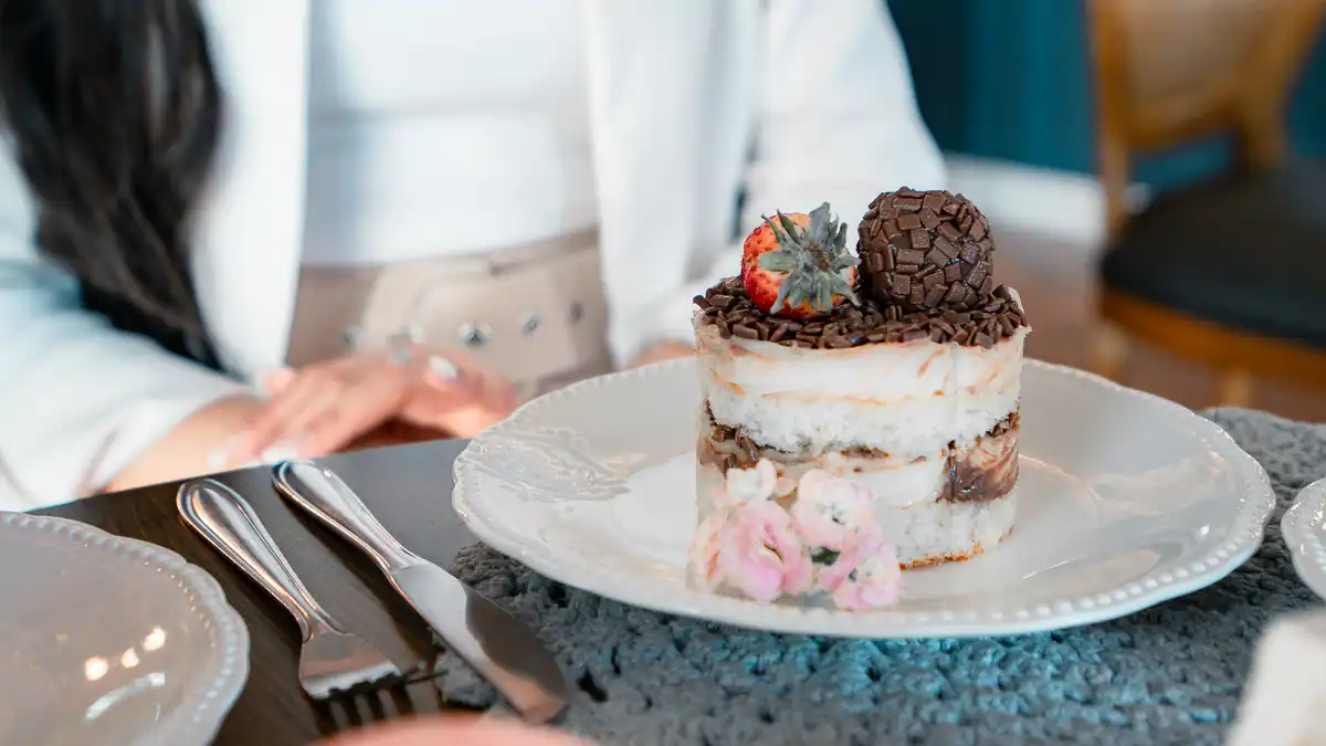 Sobremesa de chocolate com morango em prato branco sobre mesa de madeira — metáfora visual das notas comestíveis do perfume gourmand