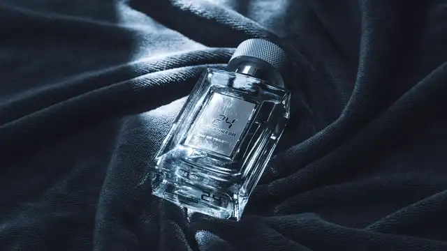 Frasco masculino de vidro sobre tecido escuro, com iluminação dramática que remete a luxo e presente sofisticado