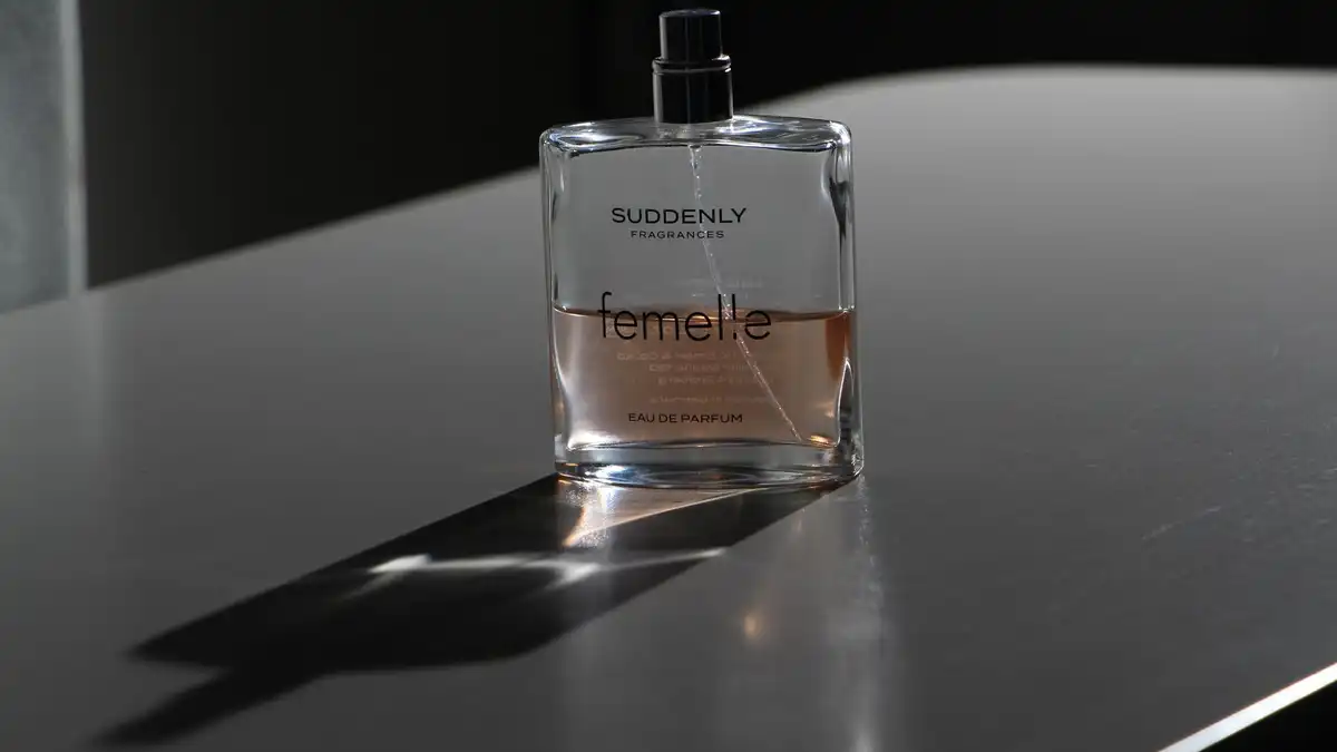 Frasco de perfume sobre superfície escura com luz suave, evocando elegância discreta no ambiente profissional