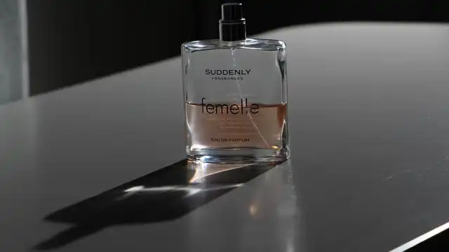 Frasco de perfume sobre superfície escura com luz suave, evocando elegância discreta no ambiente profissional
