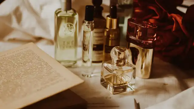 Frasco de perfume com detalhes dourados sobre superfície clara — remete à durabilidade e conservação de fragrâncias