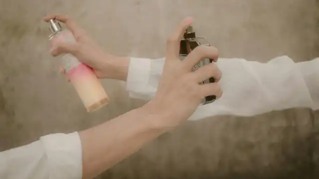 Duas pessoas borrifando perfume nos pulsos com frascos diferentes — ilustra a aplicação moderada de fragrância
