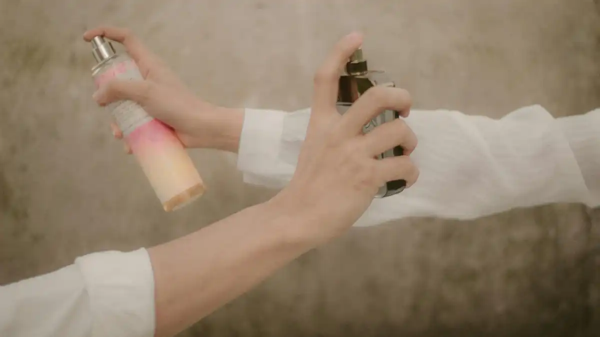 Duas pessoas borrifando perfume nos pulsos com frascos diferentes — ilustra a aplicação moderada de fragrância