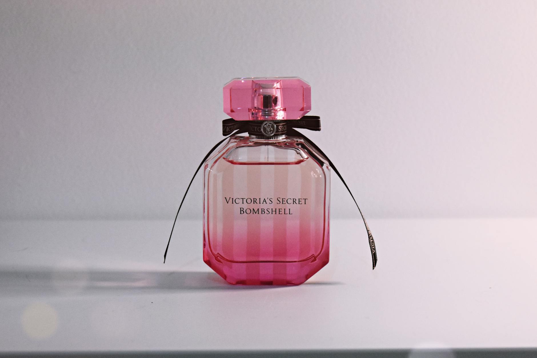 Frasco de perfume importado feminino em tom rosa sobre superfície clara e elegante