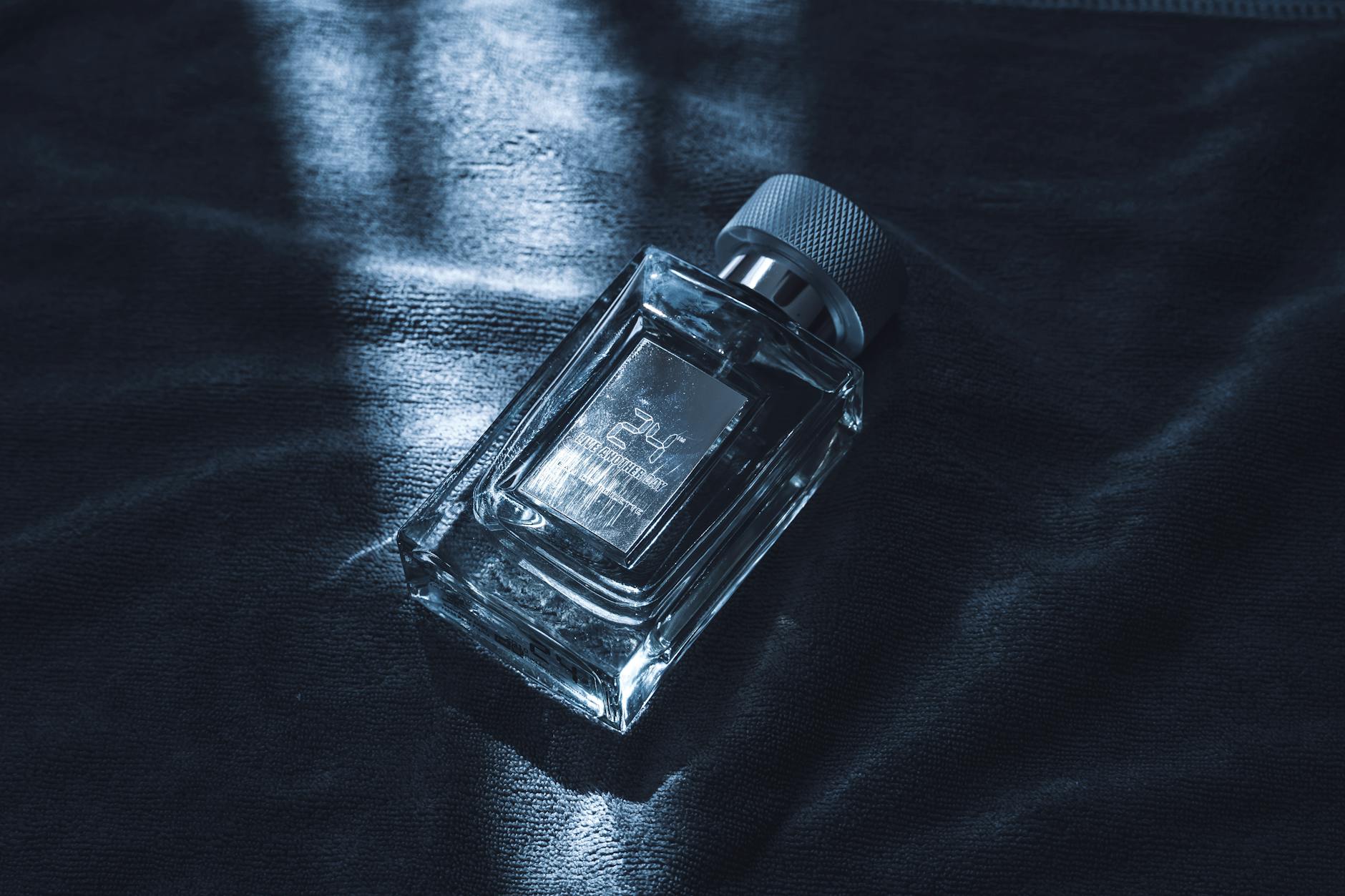 Frasco de perfume masculino de luxo em vidro sobre tecido escuro texturizado