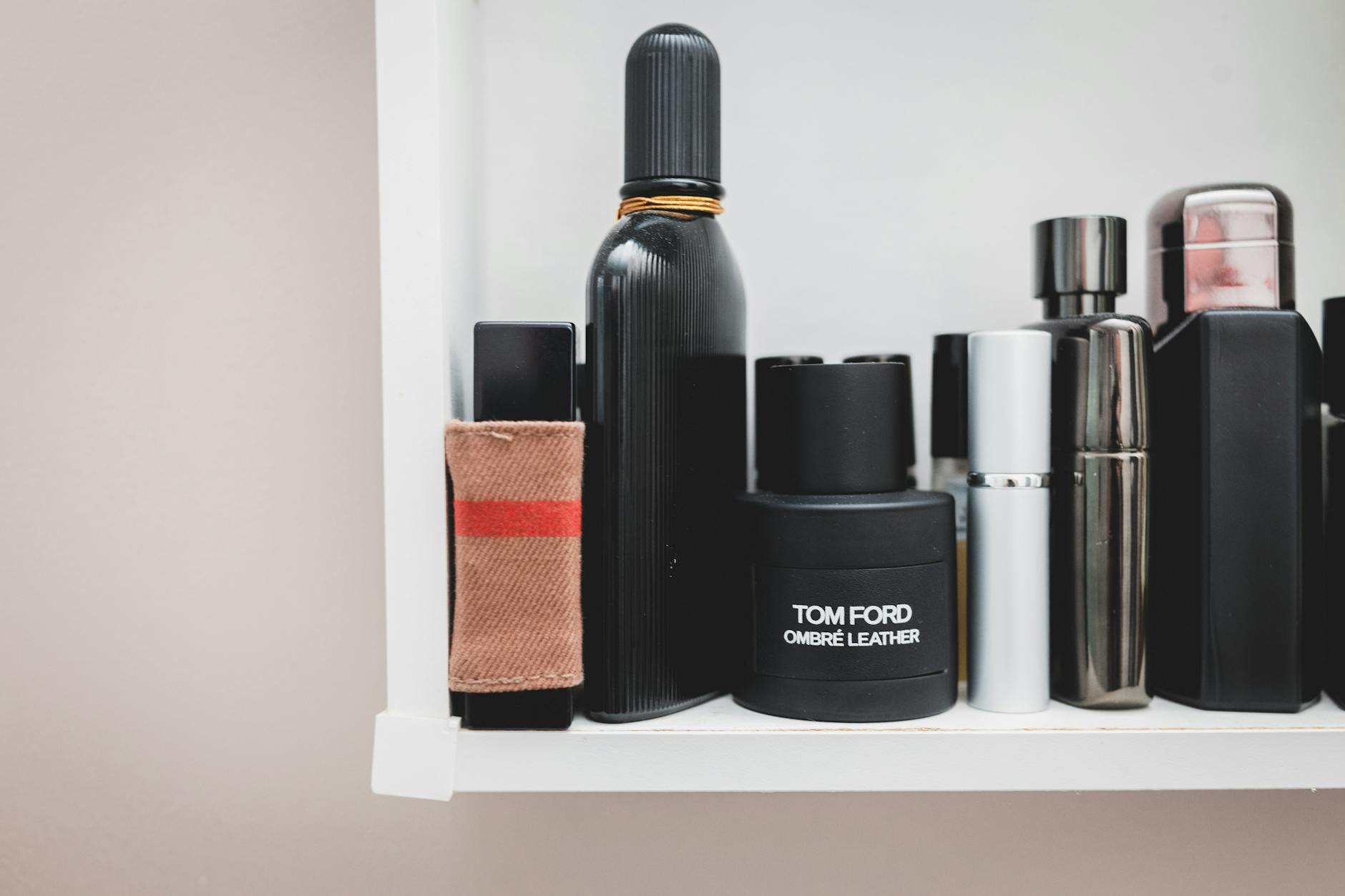 Prateleira com diversos frascos de perfumes e colônias masculinas alinhados