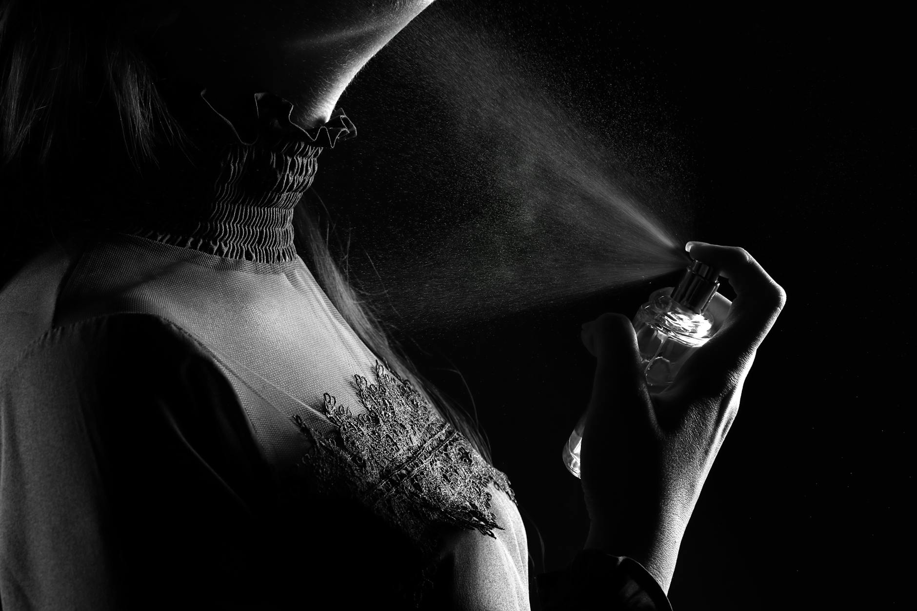 Mulher borrifando perfume no pescoço em foto em preto e branco